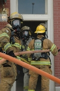 firefighters gather at door of building to fight fire